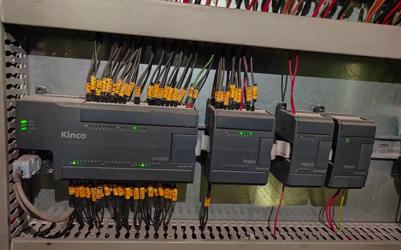 A row of PLCs and I/O modules wired on a cabinet backplate with numbered ferrules