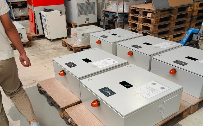 A batch of finished control boxes standing on pallets in a workshop