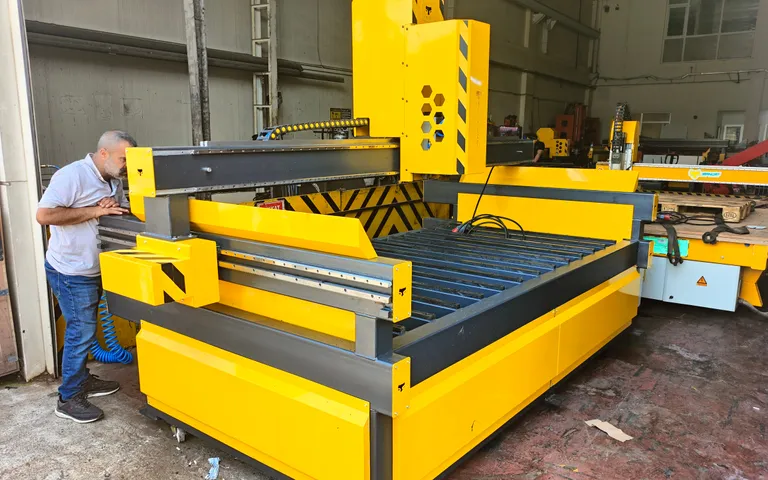 Operator working at a large CNC router with a gantry over a flat bed