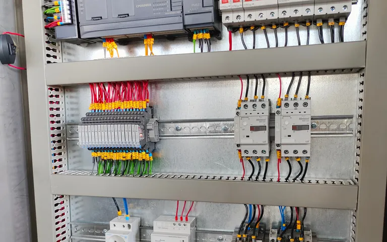 Cabinet backplate carrying a controller, breakers and contactors with wiring dressed into ducts