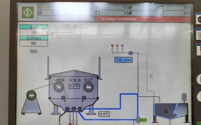 Machine interface showing a process graphic with an active alarm banner across the top
