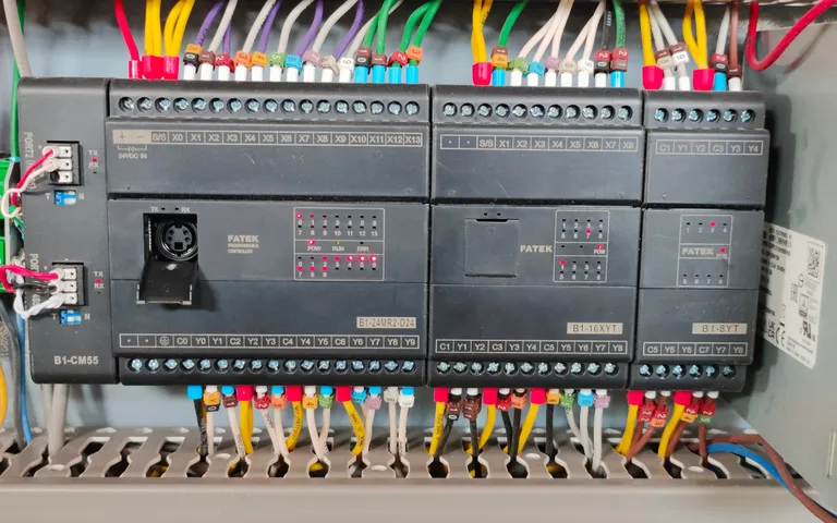 Four controllers side by side on a rail above densely ferruled terminal blocks